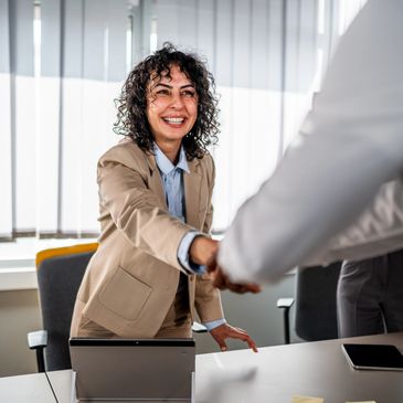 Smiling businesswoman shaking hands in office meeting.