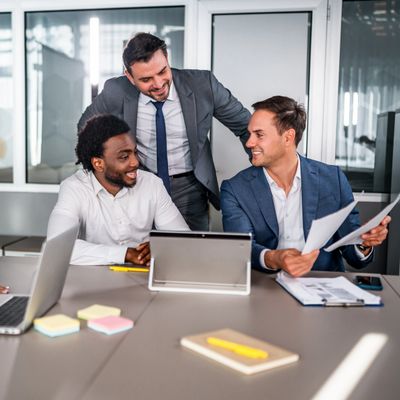 Three businessmen collaborating happily in a modern office meeting.