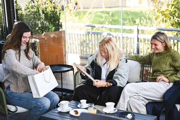 Three women enjoying coffee and conversation on a cozy outdoor patio.