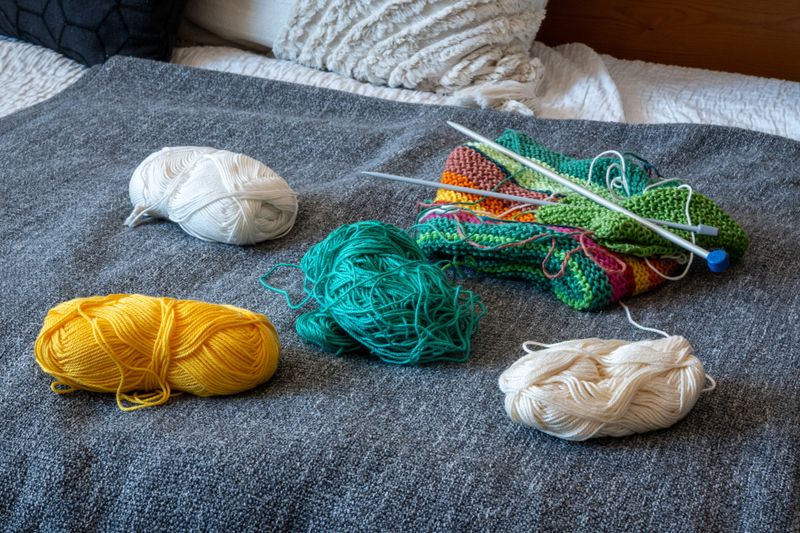Colorful Yarn Balls and Knitting Needles on Cozy Blanket. Knitting project with crochet supplies. Creative home hobby for winter. Craft materials. Slow living