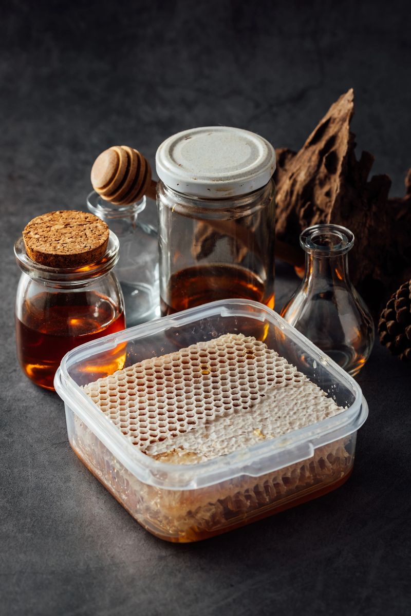 A beautiful arrangement featuring fresh honeycomb in a clear container alongside various glass jars filled with honey. Ideal for food photography or culinary-themed projects.