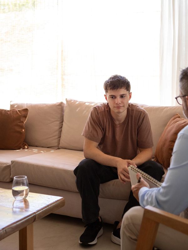 A young man talking to a therapist in a cozy living room.