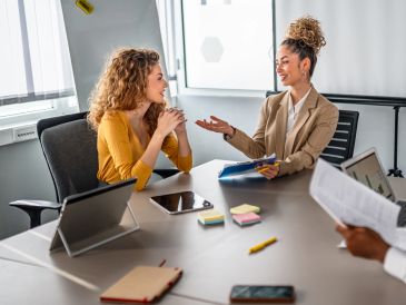 Two women engaged in a friendly business meeting in a modern office.