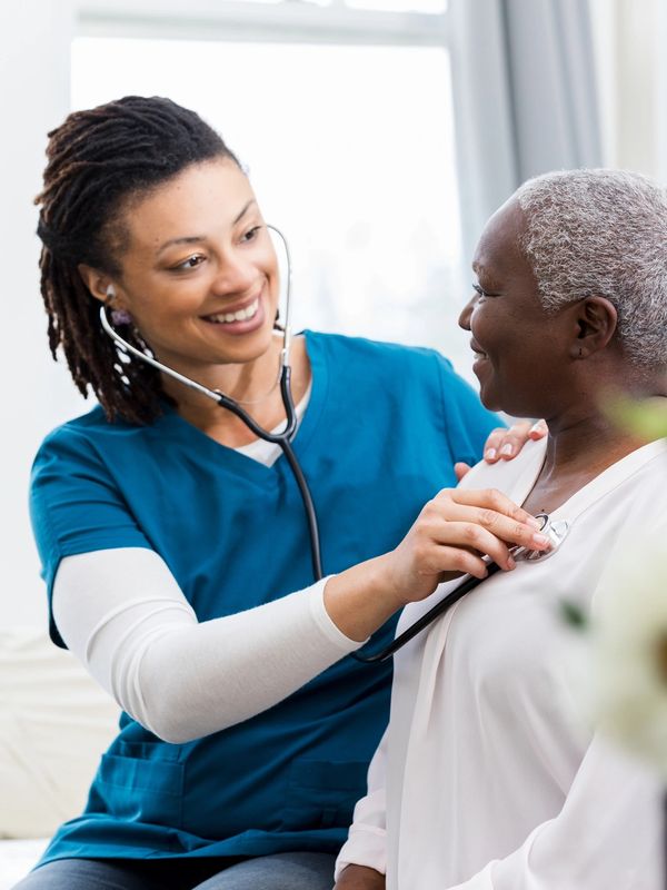 Nurse checking an elderly woman's heart with a stethoscope.