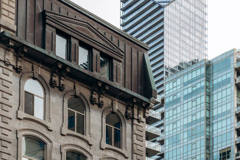 Historic stone architecture contrasting with modern glass skyscrapers in downtown Montreal, Quebec