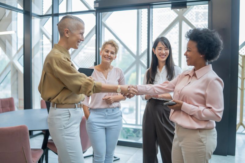 Four businesswomen shaking hands after reaching an agreement in a modern office