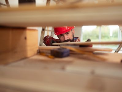 Carpenter measuring wood with a tape.