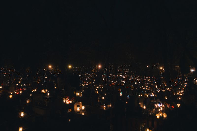 A sea of candles illuminates a cemetery, creating a poignant and reverent atmosphere under the night sky