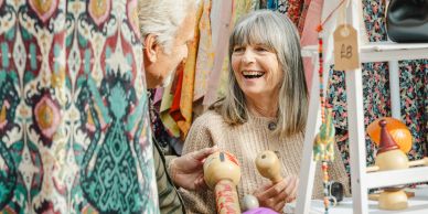 Two seniors enjoy shopping at a market stall.