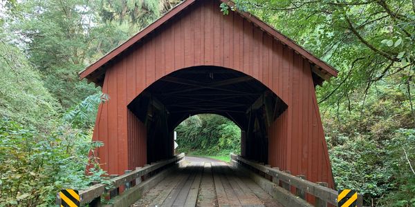 A red covered wooden bridge surrounded by greenery.