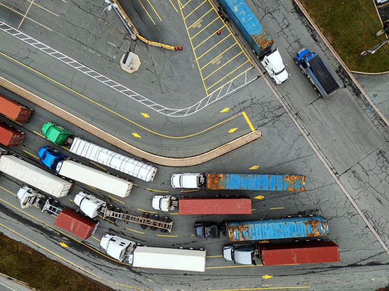 Aerial view of a long queue of semi trucks waiting to unload/load their cargo at a container terminal.