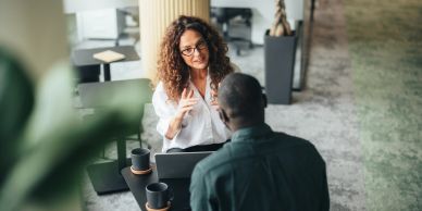 Two colleagues engaged in a discussion over coffee in a modern office.