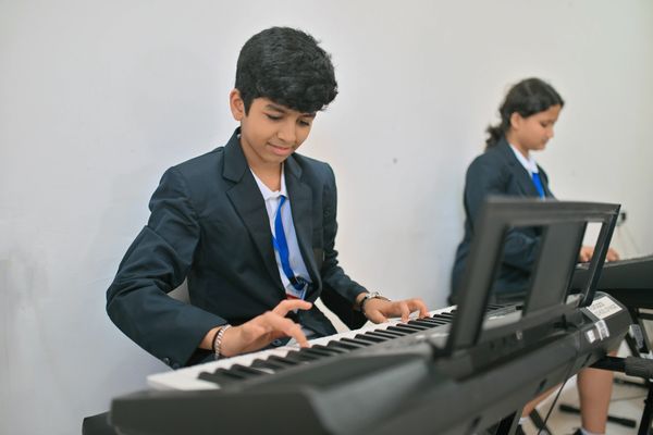 Two students playing keyboards in a music class.