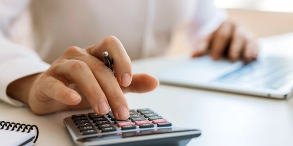 Person using calculator and laptop, focusing on calculations.