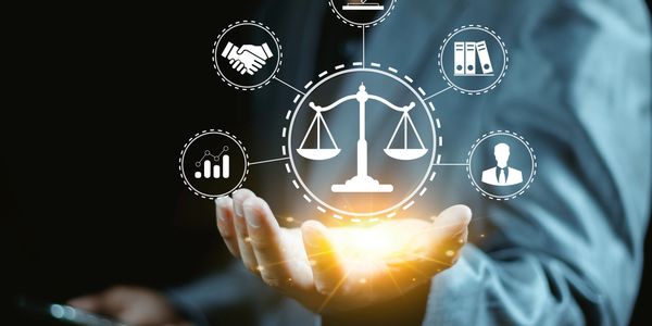 Hand holding glowing legal scales surrounded by law and business icons.