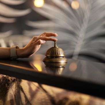 Hand pressing a service bell on a counter.