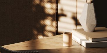 Sunlight casting shadows on a table with books and a vase.