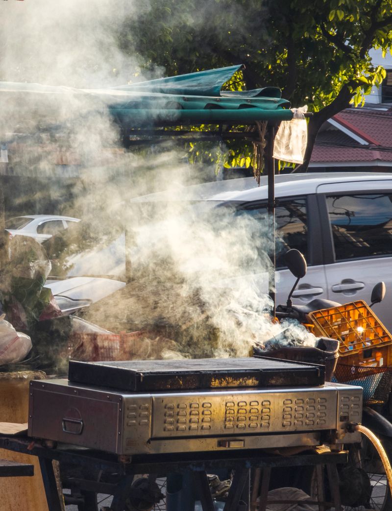 At sunset,outside the Old City walls,thick smoke fills the air from outdoor sidewalk food vendor stalls as they prepare to cook grilled meat and snacks for the evening.