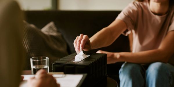 Person pulling tissue from a box during a counseling session.