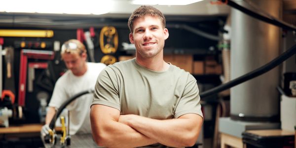 Smiling man with crossed arms in workshop.