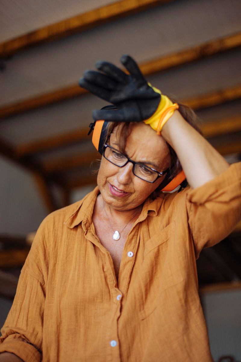 Portrait of a woman working in her small business, looking visibly tired as she exhales and wipes sweat from her forehead. Her facial expression shows exhaustion, effort, and determination after a demanding task. The scene captures the reality of running a small business, highlighting hard work, dedication, and the challenges behind everyday entrepreneurship.