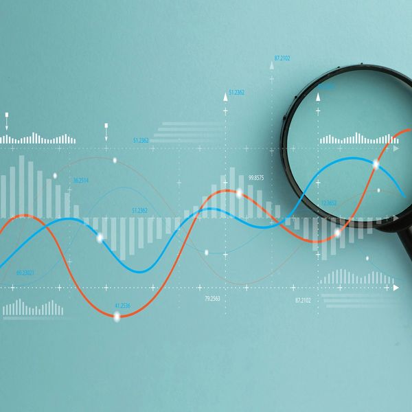 Magnifying glass over financial graphs and data analytics on a blue background.