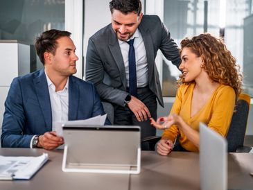 Three colleagues engaged in a business discussion in a modern office.