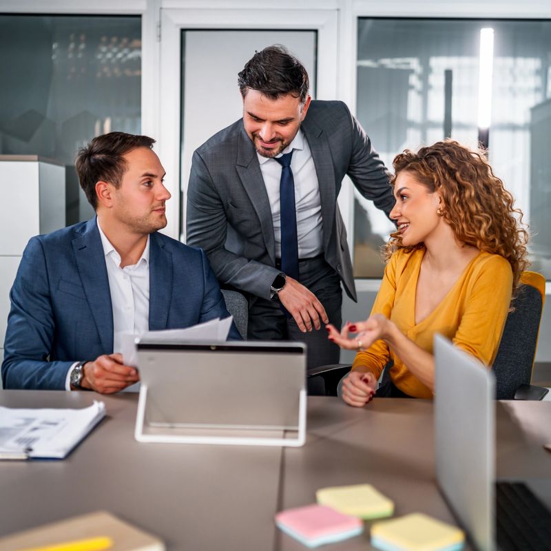 Three business professionals discussing new ideas and working together in a modern office meeting room, fostering innovation