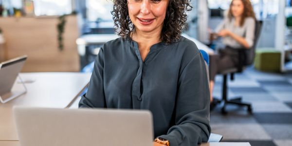 Smiling woman working on a laptop in a modern office.