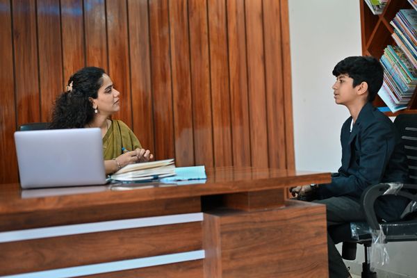 Teacher and student engaged in a serious conversation in an office setting.