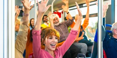 Happy people raising hands on public transport.