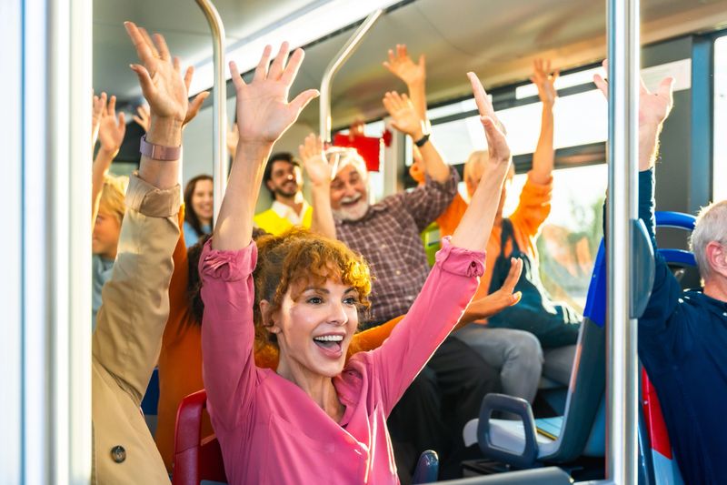 Group of happy passengers with raised arms celebrating and enjoying the ride on public transportation, sharing a moment of excitement and connection during their journey