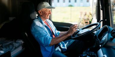 Older man using a tablet while sitting in a truck cabin.