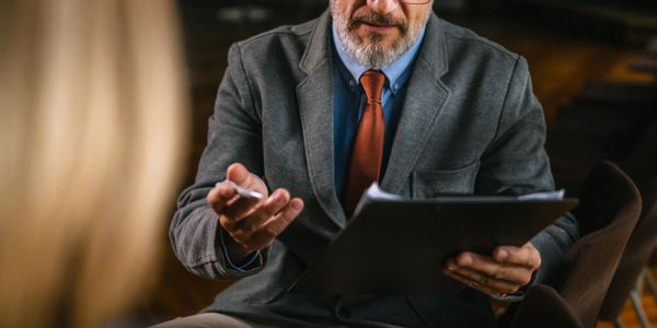 A mature man in glasses discussing documents with a woman.