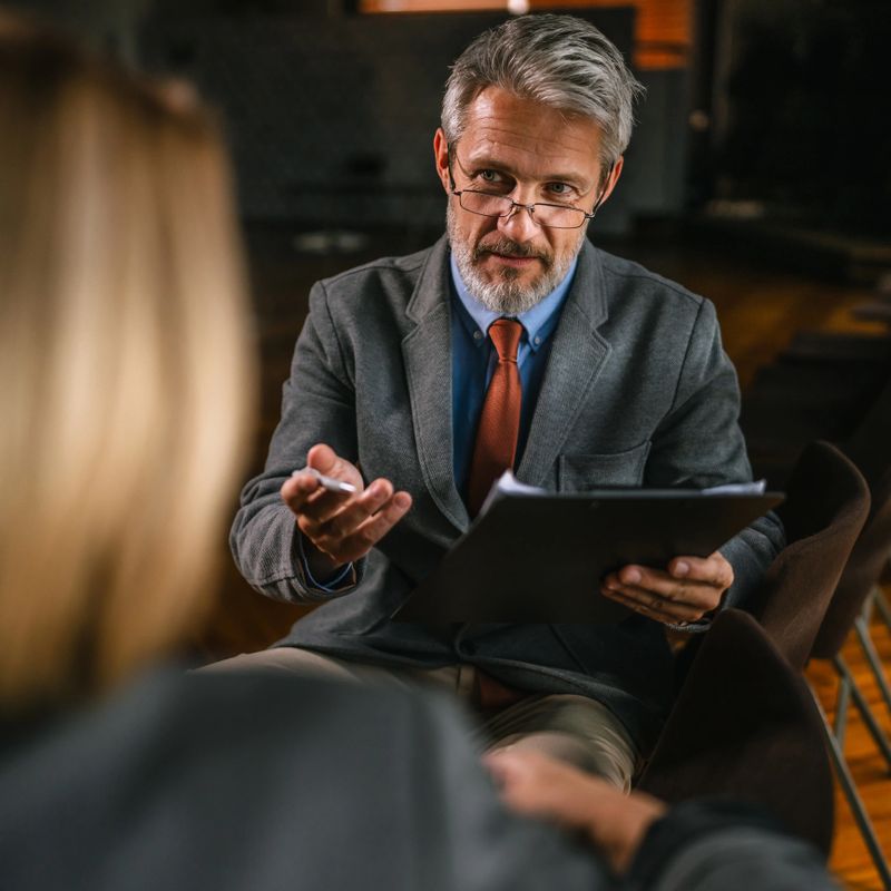Experienced hr manager leading a job interview, reviewing the candidate's resume and qualifications during a professional business meeting in a modern office environment
