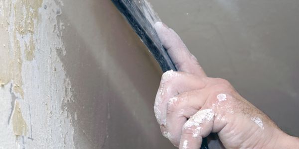 Hand sanding a wall with sandpaper.