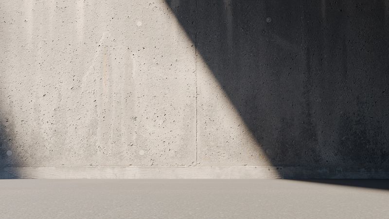 scene shows a textured concrete wall with a prominent shadow extending across the smooth floor. Soft natural light enhances the contrast, creating an interesting visual effect. 3d render.
