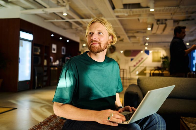 Young adult man working on his laptop in a contemporary office setting