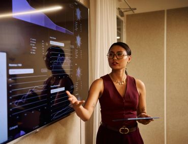 Woman presenting data on a large screen.