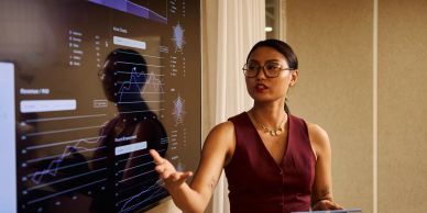 Woman presenting data on a large screen.