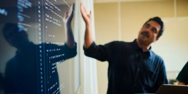 Man explaining code on a transparent board.