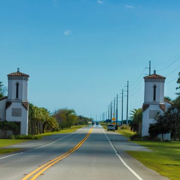 Gated community entrance with towers on both sides and a clear blue sky.