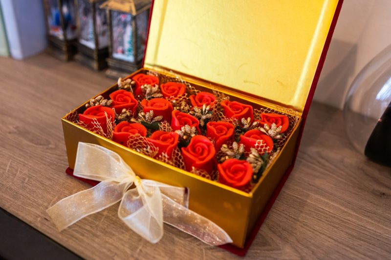 Gift box with artificial red roses and decorative ribbon. Romantic present, festive packaging and elegant celebration atmosphere