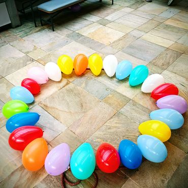Colorful balloons arranged in a heart shape on tiled floor.