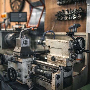 Industrial lathe machine in a workshop with control wheels and digital display.