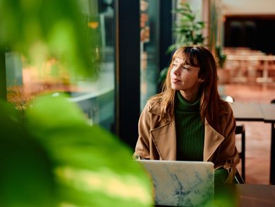 Woman enjoying a peaceful moment by the window with a laptop.