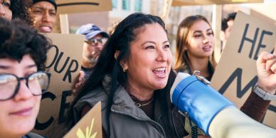 A woman leads a protest with a megaphone.