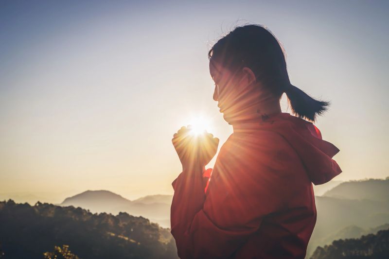 Girl praying to god on mountain sunset background