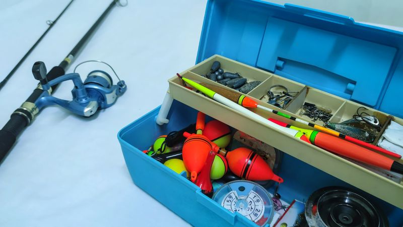 A clear, close-up shot of fishing equipment including a rod and an organized box of accessories, suitable for outdoor or sporting concepts.