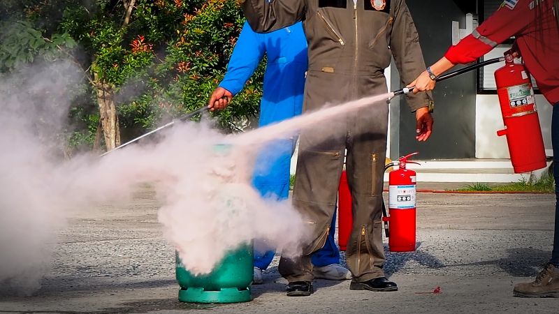 A person’s hands actively attempting to extinguish a small flame, representing safety, quick response, and emergency action.
